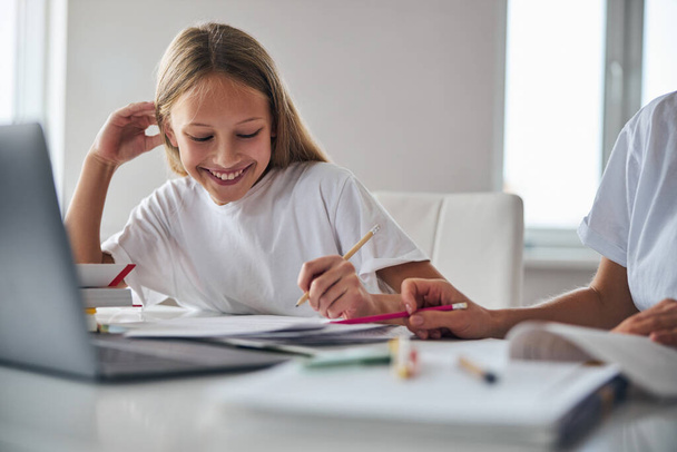 Cheerful teenager holding a pencil over some papers - Fotoğraf, Görsel