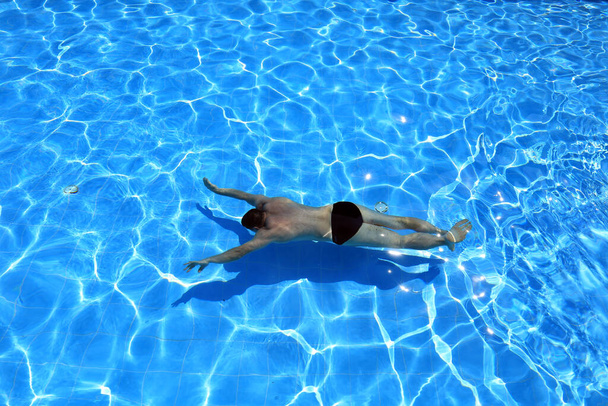 απομονωμένη γαλάζια πισίνα νερού και κολυμβητής στο νερό  - Φωτογραφία, εικόνα