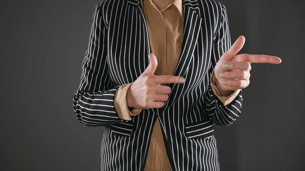 Woman in suit shows two fingers to the side - Fotoğraf, Görsel