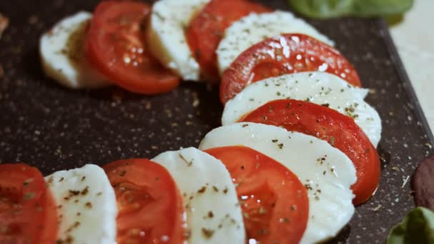 Caprese - italian national dish. Sliced tomatoes and mozarella arranged in shape of Christmas candy cane. Served with basil and olive oil. Slowmotion. Macro view - Footage, Video