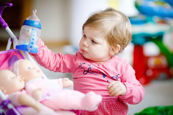 Cute adorable baby girl holding nursing bottle and drinking formula milk or water. First food for babies. Healthy babies and bottle-feeding concept for children - Valokuva, kuva
