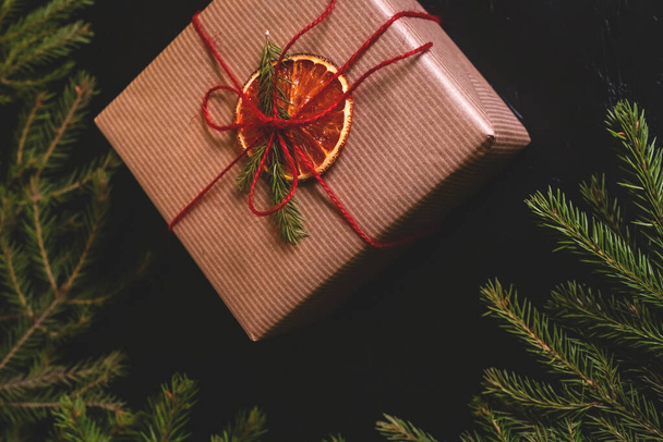 Karácsonyi kompozíció. Kézzel készített ajándékdoboz, kézműves papírral díszítve, sötét hátterű ebédekkel. Fénymásolási hely - Fotó, kép