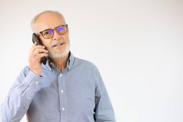 Senior man having conversation talking on the phone over white background with a happy face standing and smiling with a confident smile - Fotografie, Obrázek
