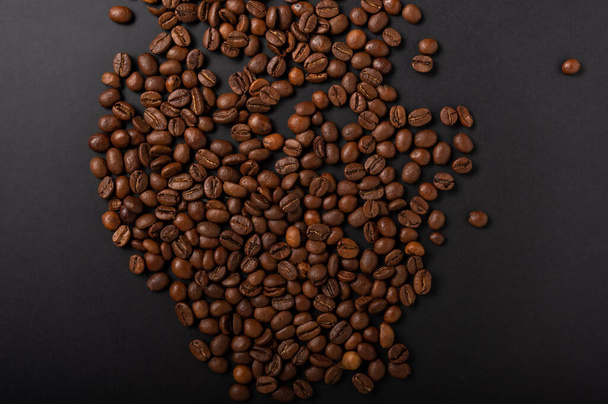 Sprinkled coffee beans in the center of the table. Grains on a black background. Flat lay. - Photo, Image