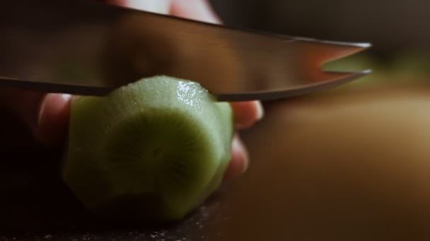 Rebanando un jugoso kiwi verde en una tabla de cortar de mármol negro. Vista macro - Imágenes, Vídeo