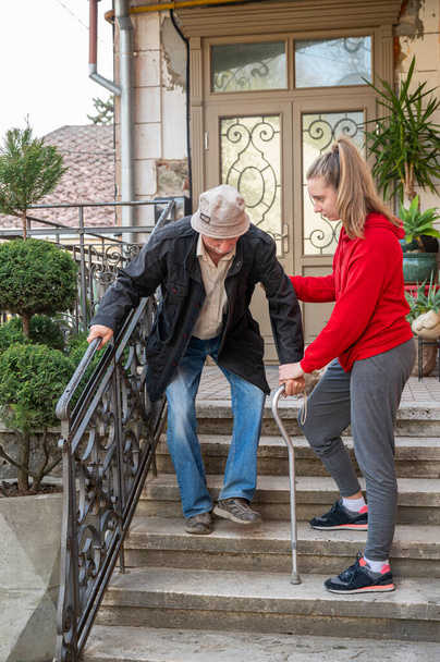 Hombre mayor con bastón caminando con su nieta al aire libre - Foto, imagen