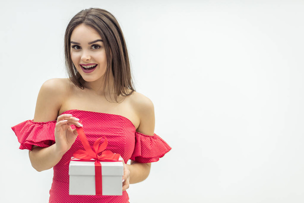 Holiday celebration concept. Curious young woman holding a present box eager to fing out wht is inside. - Foto, Imagen