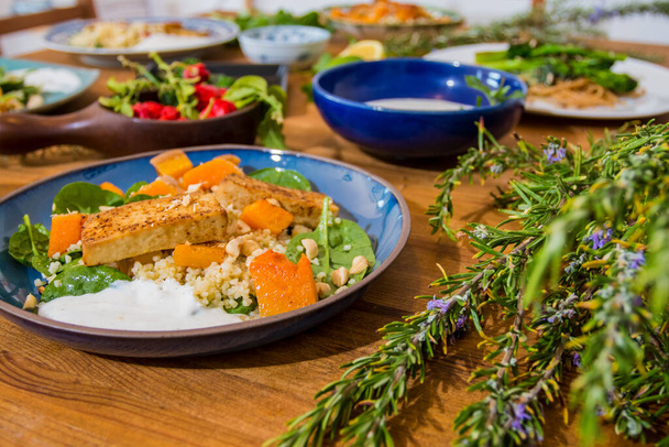 Ψητά λαχανικά και υγιεινά πιάτα σε ένα φανταχτερό ξύλινο τραπέζι. Μεσογειακά πιάτα με σπαράγγια, τόφου, σεϊτάν και χαλούμι. Συνταγές χωρίς γλουτένη για γυμναστές. Ιστορικό τροφίμων - Φωτογραφία, εικόνα