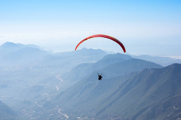 Türkiye 'nin Antalya ilinin Türk Rivierası' ndaki bir sahil beldesi olan Kemer yakınlarındaki dağların üzerinden uçan Paraglider - Fotoğraf, Görsel