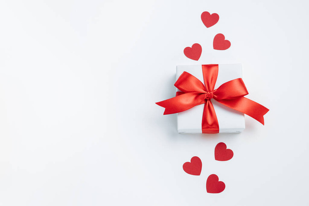 Gift box with red ribbon and hearts on white background. Valentines day banner with free space. Top view, flat lay. - Photo, Image
