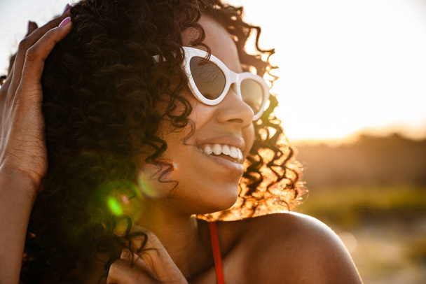 Image of amazing beautiful happy young african woman walking at the beach outside in sunglasses - Foto, imagen