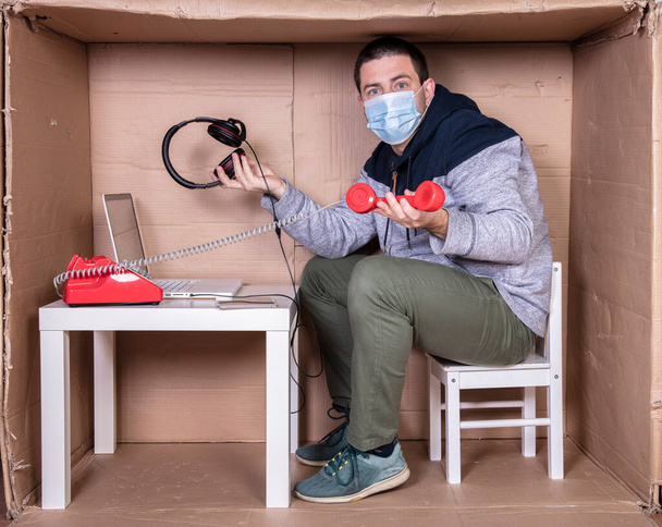 werknemer werkt vanuit zijn eigen kartonnen kantoor om zich te isoleren van anderen - Foto, afbeelding