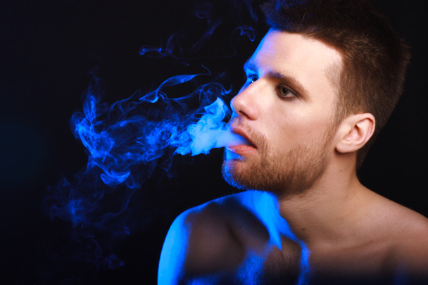 Close up portrait of young man smoking cigarette - Photo, Image