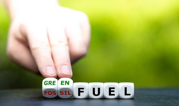 Hand turns dice and changes the expression "fossil fuel" to "green fuel". - Photo, Image