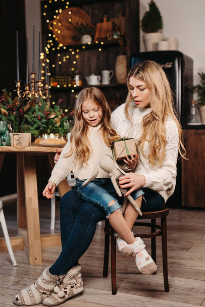 Beautiful mother giving little daughter a christmas gifts at home - Фото, изображение