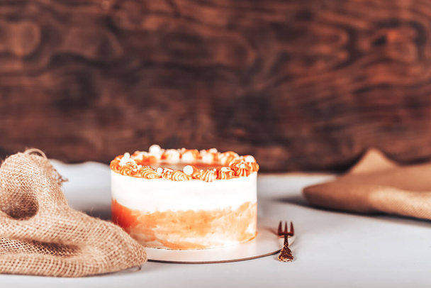 Kuchen auf einem weißen Teller mit einer Gabel vor einem hölzernen Hintergrund. Süßigkeiten für jeden Urlaub. - Foto, Bild