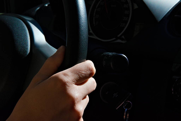 Weibliche Hand am schwarzen Lenkrad eines Autos während der Fahrt. Aus nächster Nähe. . Hochwertiges Foto - Foto, Bild