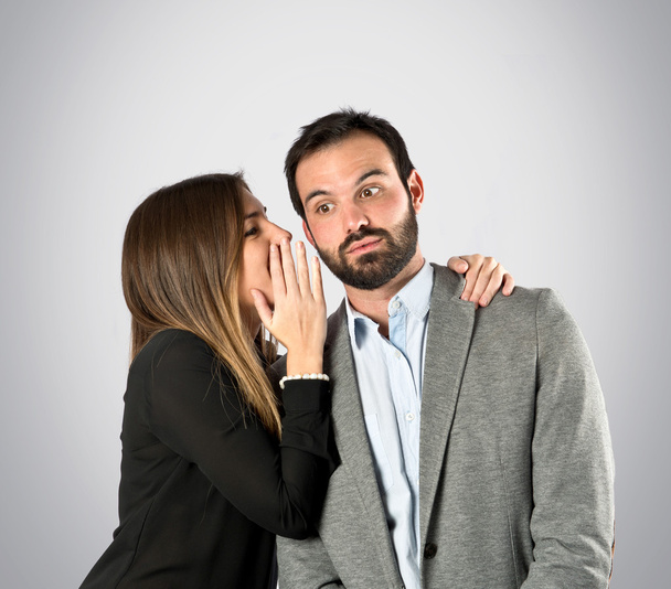 jeune fille chuchotant à son petit ami sur fond gris
 - Photo, image