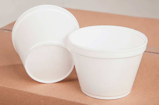 Closeup white foam cups stand on a cardboard box on an isolated background. - Zdjęcie, obraz