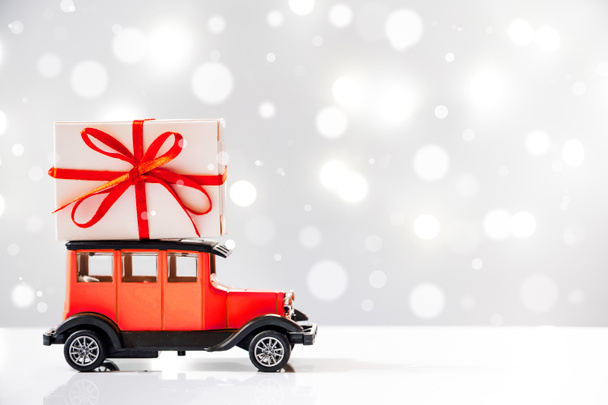 Доставка подарков к празднику. Ретро игрушечный автомобиль с подарочной коробкой на крыше. - Фото, изображение