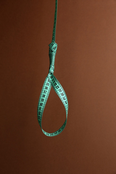 Tape measure noose on brown background - diet concept - Фото, изображение