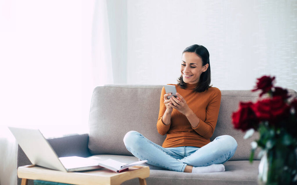 Happy excited beautiful woman with smart phone on the couch - Foto, Imagem