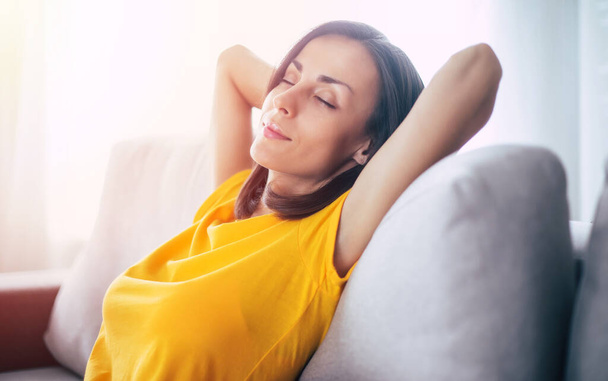 Beautiful calm confident brunette woman is resting on the couch at home during holidays - Фото, зображення