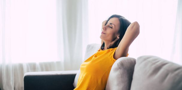 Beautiful calm confident brunette woman is resting on the couch at home during holidays - Φωτογραφία, εικόνα