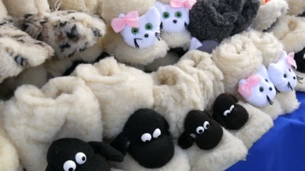 公正な市場のカウンターで羊のウールで作られた面白い暖かい家庭用スリッパ。寒い冬の準備 - 映像、動画