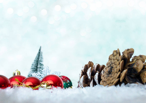Kerst ornamenten, mini dennenboom en dennenappels op sneeuw met kopieerruimte, vooraanzicht - Foto, afbeelding