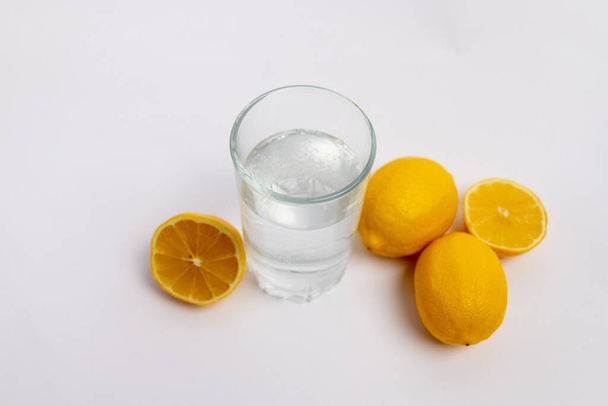 a glass of water and lemons on a white isolated background - Foto, Bild