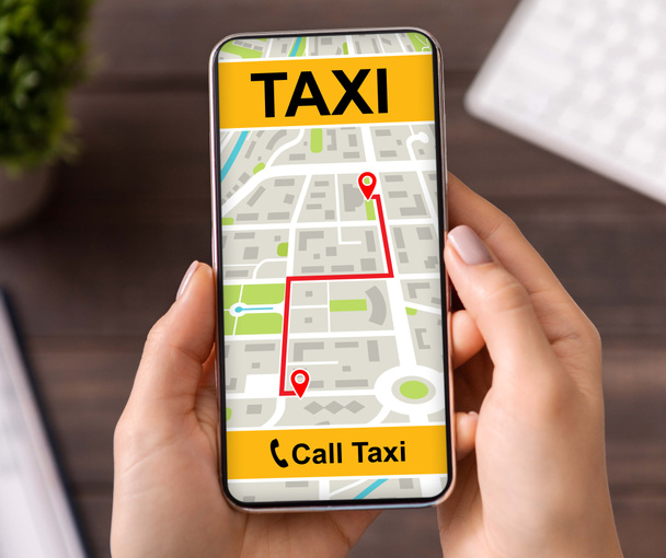 Mujer joven sosteniendo teléfono inteligente con interfaz de aplicación de taxi - Foto, Imagen
