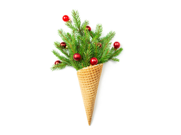 Waffle cone with spruce twigs and Christmas toys. White isolated background. New Year. Christmas card. Copy space, flat lay. The concept photo is an original Christmas present. - Photo, Image