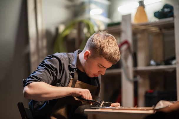 a young master in the manual production of shoes in his workshop is working on creating shoes. - Valokuva, kuva