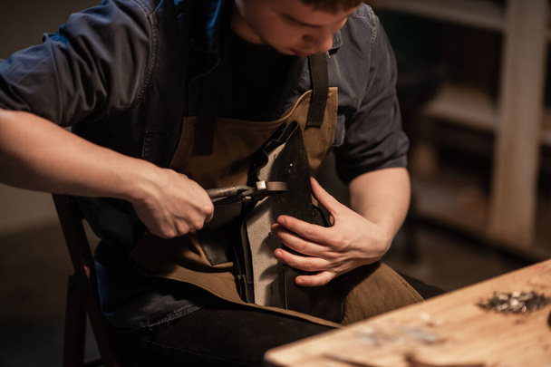 a young talented shoemaker in the workshop is engaged in manual production of shoes made of leather. - 写真・画像