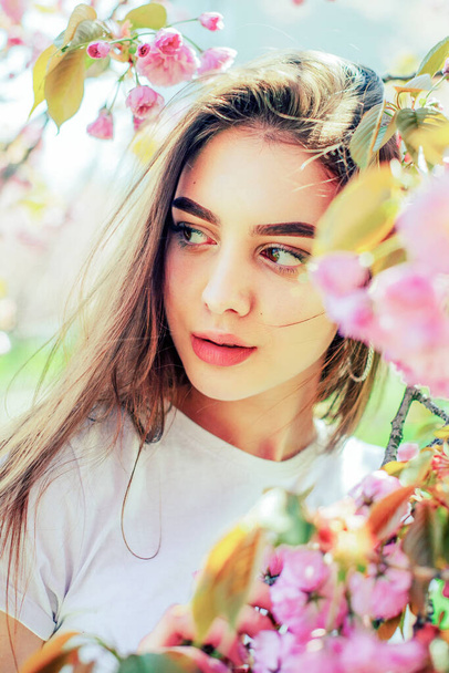 Giovane bella ragazza con i capelli lunghi gode la bellezza della natura primaverile vicino al sakura in fiore - Foto, immagini