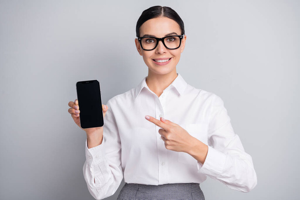 Photo of girl hold phone direct finger screen empty space wear eyeglasses white shirt isolated grey color background - Φωτογραφία, εικόνα