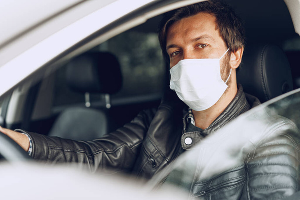 Jongeman in een auto met medisch masker - Foto, afbeelding
