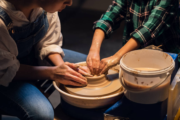 una giovane madre con un figlio affascinante in un laboratorio di ceramica che scolpisce un vaso. - Foto, immagini