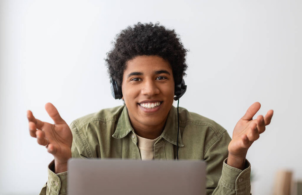 Online onderwijs of communicatie concept. glimlachen zwart tiener in hoofdtelefoon praten met zijn universiteit tutor op web - Foto, afbeelding