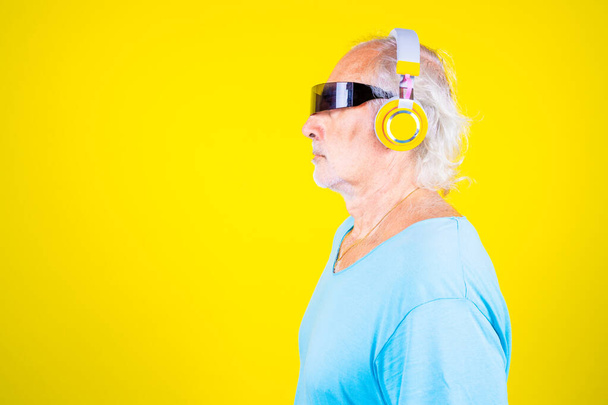 Älterer Kaukasier mit smarter Brille auf gelbem Hintergrund erlebt Augmented Reality - Foto, Bild