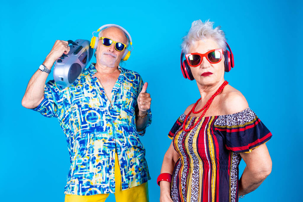 Paar von älteren Mann und Frau auf blauem Hintergrund clubbing tanzen Spaß haben isoliert halten Vintage-Stereoanlage - Foto, Bild
