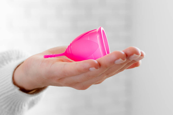 Woman in white sweater holding pink menstrual cup in hands close up - Fotoğraf, Görsel