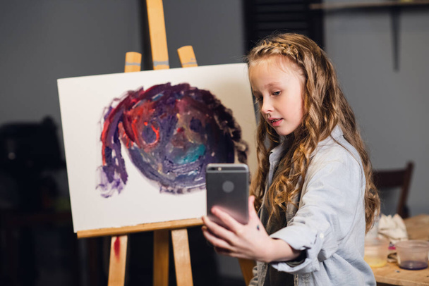 une jeune artiste charmante dirige une masterclass en ligne dans le dessin d'images dans son atelier. - Photo, image