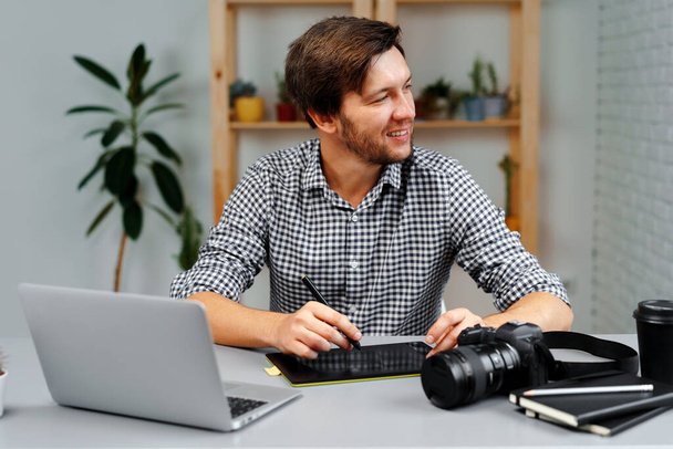 Young man photographer sits at table and works from home - Photo, image