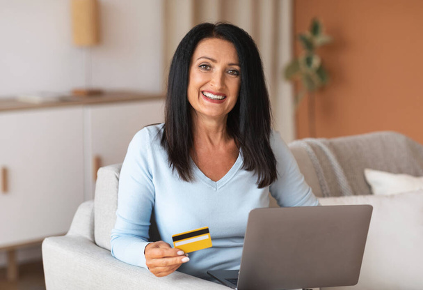Mulher madura fazendo compras usando o cartão de retenção do laptop - Foto, Imagem