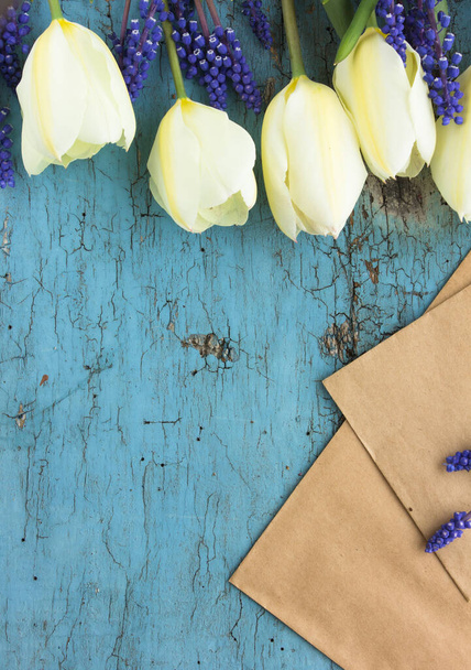 Квіти обрамляють білі тюльпани на синьому дерев'яному тлі. Вид зверху з пробілом для копіювання
 - Фото, зображення