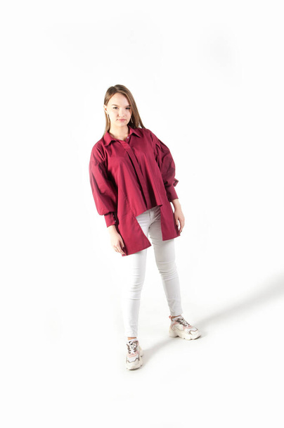 Teenager girl in red shirt and white jeans on white background - Foto, Imagen