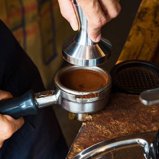 Barista drží manipulaci a portafilter s kávou pro přípravu kávy espresso. Koncept přípravy kávy. - Fotografie, Obrázek