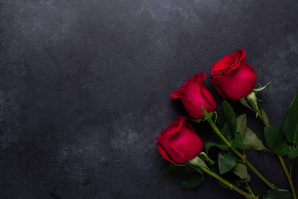 Red rose flowers bouquet on black stone background Valentine's day greeting card Copy space Flat lay - Φωτογραφία, εικόνα